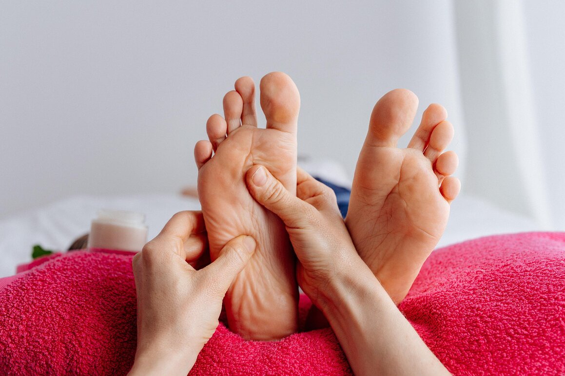 Reflexology treatment with hands working on the sole of a foot